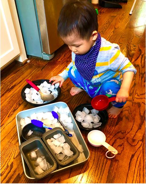 Toddler Playing with ice cube sensory Bin