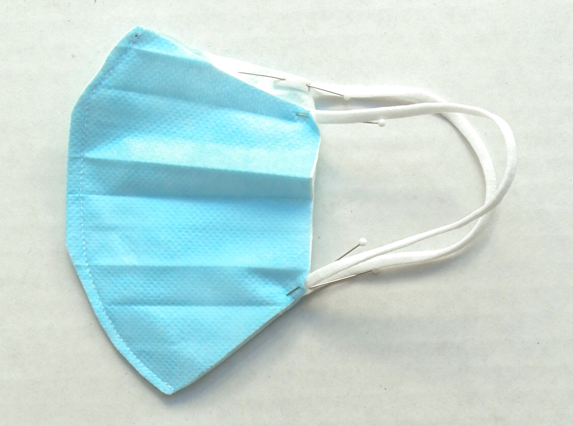Shows side of toddler surgical mask with ear loops pinned in
