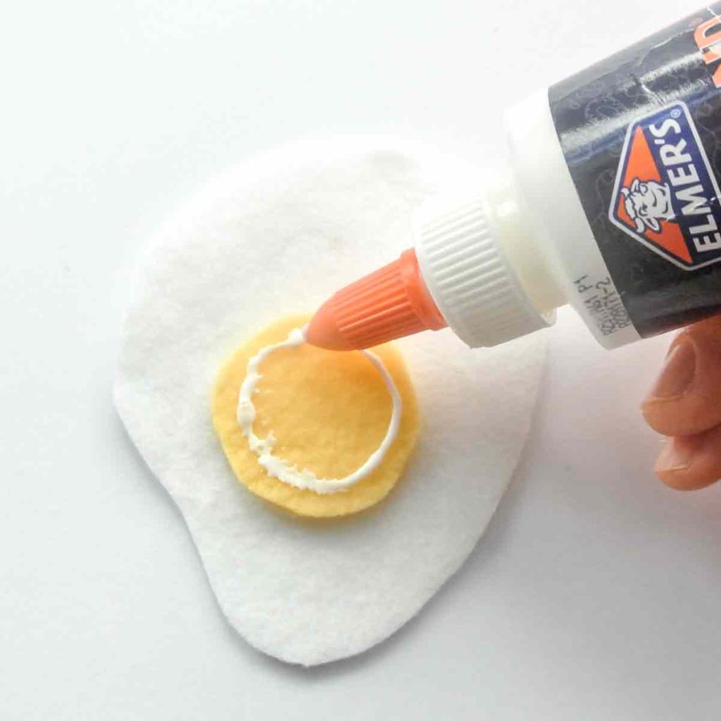 Shows fabric glue adhereing yolk on white felt egg