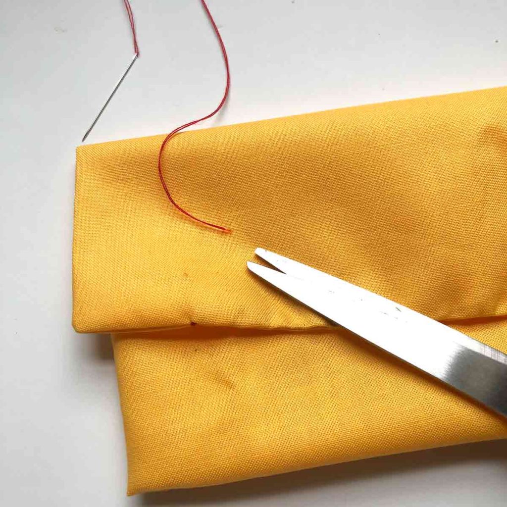 Scissor trimming off excess thread of invisible ladder stitch.