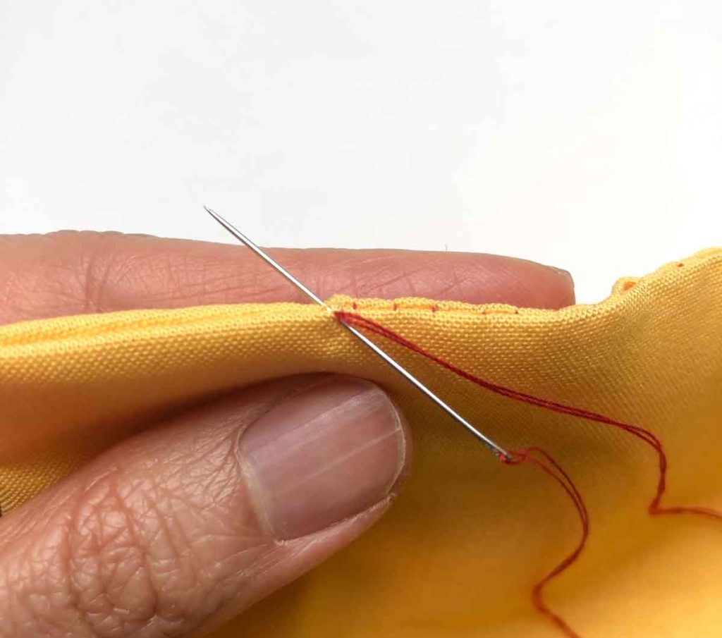 Shows needle poking through end of opening closed with ladder stitch. 