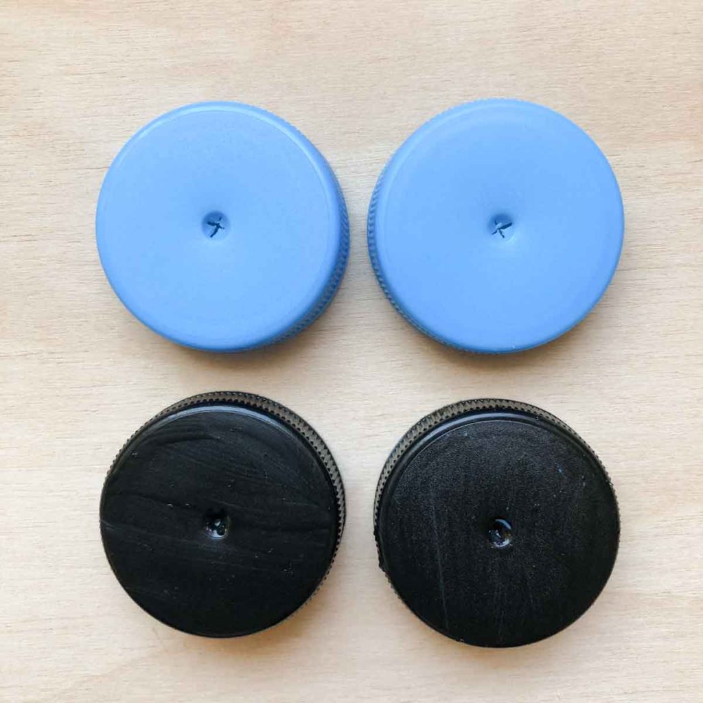 Shows 4 bottle caps punctured with holes. Bottom two caps are painted black