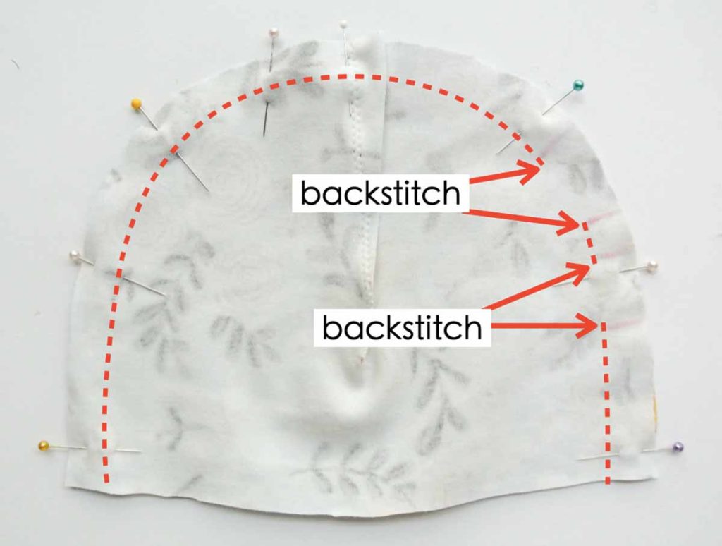 Shows how to sew Knotted Bow Baby Hat together, leaving two openings in front, with text overlay "backstitch" at red arrows