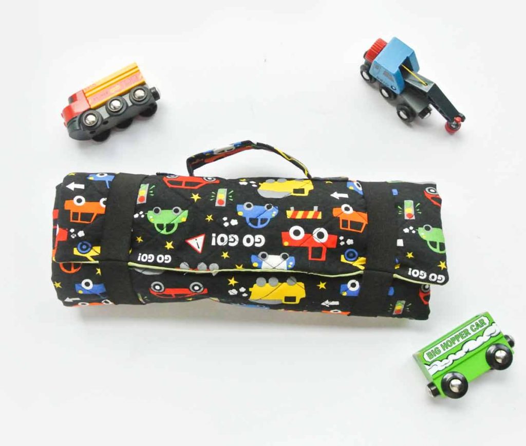 DIY Toy Car Playmat Carrier case rolled up with toy vehicles next to it.