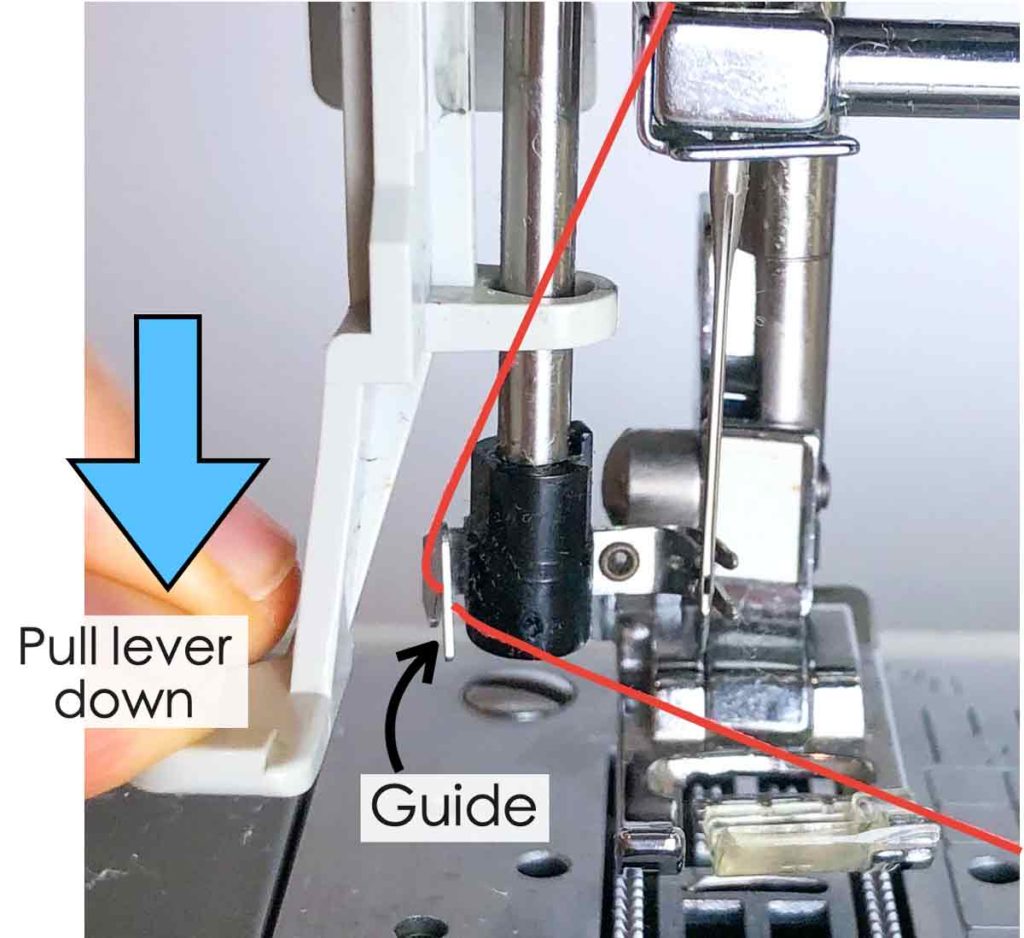 How to use built-in needle threader. Shows left hand pulling needle threader level down and right hand (not in photo) pulling thread over needle threader guide