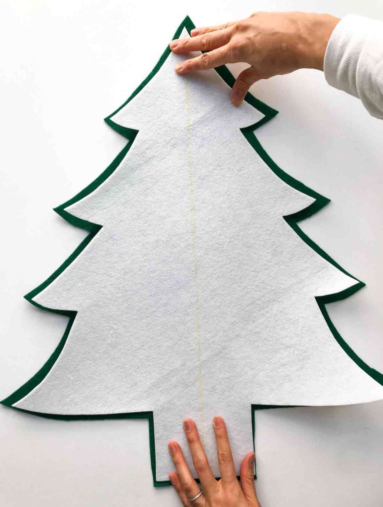 How to make a 3D Felt Christmas Tree with Free Printable pattern. Shows hands placing stabilizer over felt tree piece. 