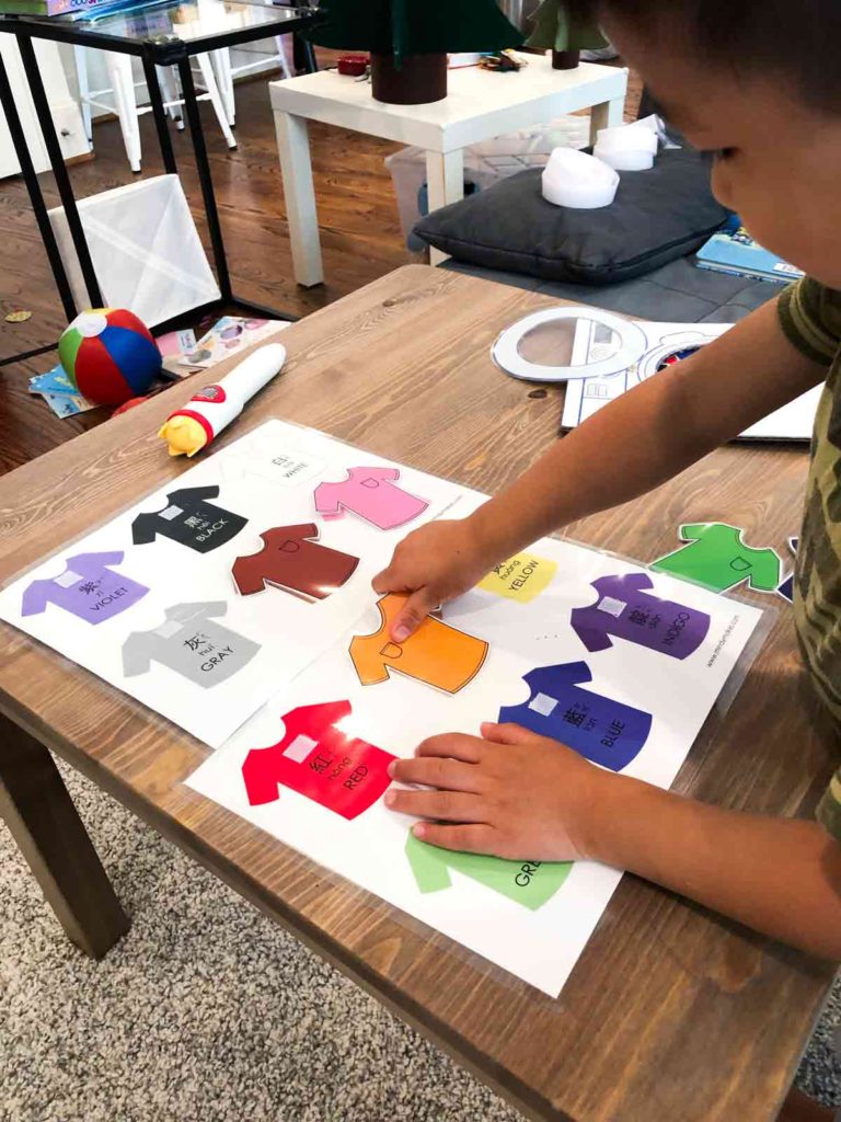 Shows toddler playing with colored shirt sorting and matching activity 