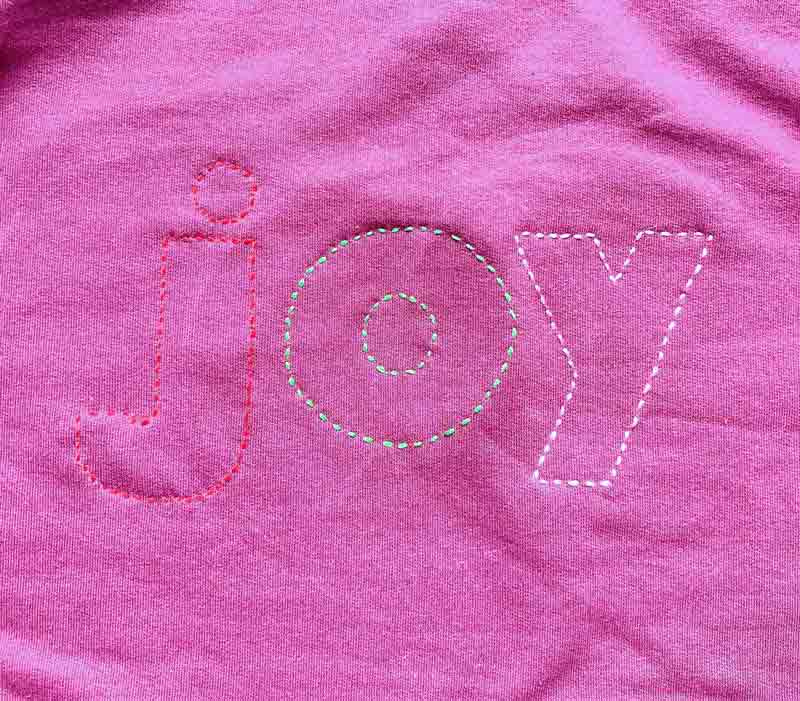 'joy' design sewn on sweatshirt for reverse applique